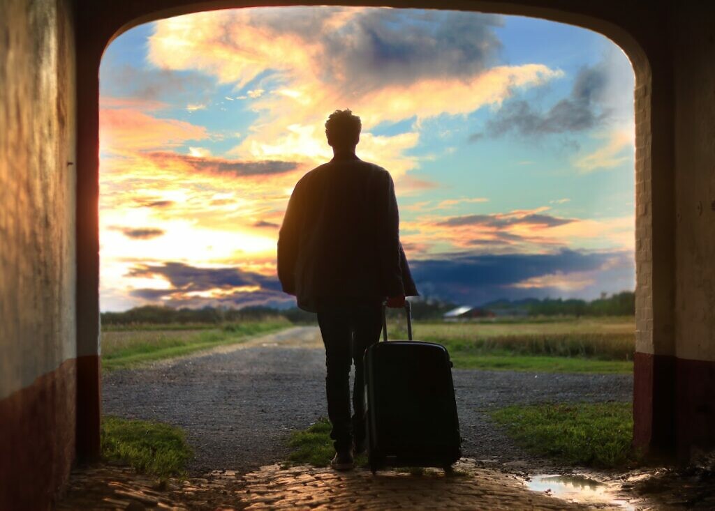 A person traveling, holding his luggage and walking.