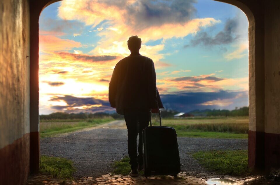 A person traveling, holding his luggage and walking in a remote place