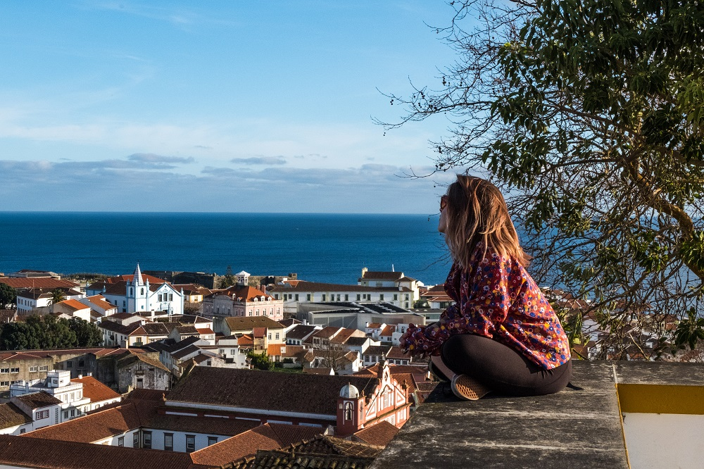 A girl sitting and slowing down while traveling. She looks at the sea while thinking. 